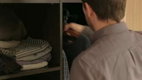 Man chooses clothes in the wardrobe in the sunlight Stock Footage 168939539