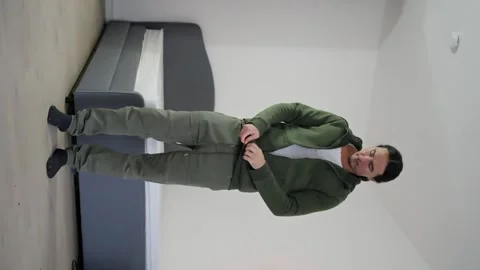 Man chooses coloured clothes, white T-shirt, hooded sweater, puts it on himself Stock Footage 263965002