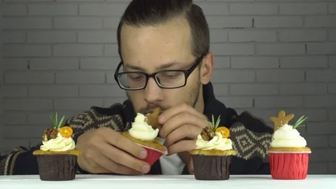 A man chooses cupcake and eats with pleasure 動画素材 99705842