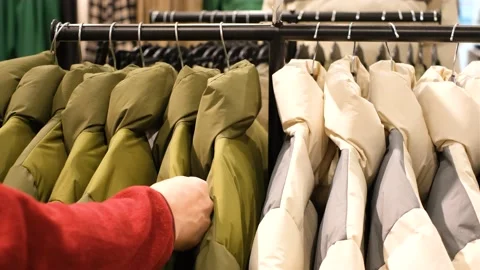 Man chooses a down jacket in a retail store, shopping concept, close-up. Stock Footage 167346397