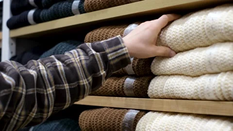 Man chooses jersey sweaters lying on shelves in the store. Stock Footage 165748185