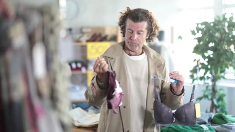 Man chooses a lace bra and a set of lingerie for wife as a gift. Buying Stock Footage 323909364