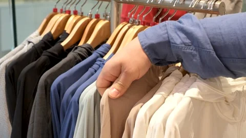 Man chooses a male windbreakers hanging on hanger in store. Stock Footage 307890904