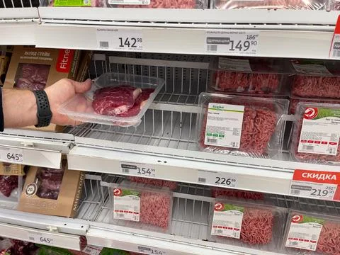 A man chooses meat in a supermarket. Stock Photos