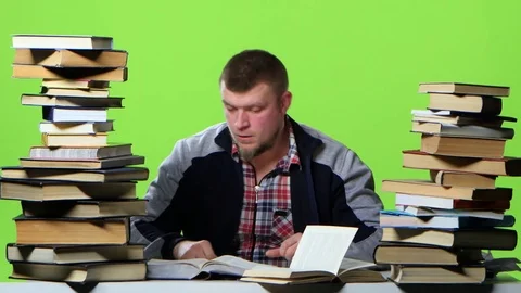 Man chooses the most interesting book, and writes in a notebook. Green screen Stock Footage