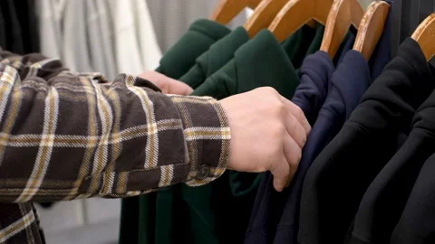 A man chooses a multicolored sweatshirt on hanger close-up. Stock Footage 165211543