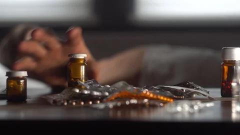 The man chooses the pills lying on the table.The man in the background Stock Footage 125809981