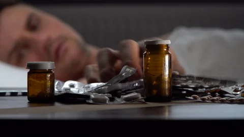 The man chooses the pills lying on the table Stock Footage 125809983
