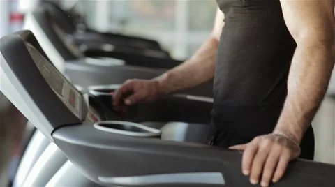 Man chooses a program on a running machine in the gym Stock Footage 56635973