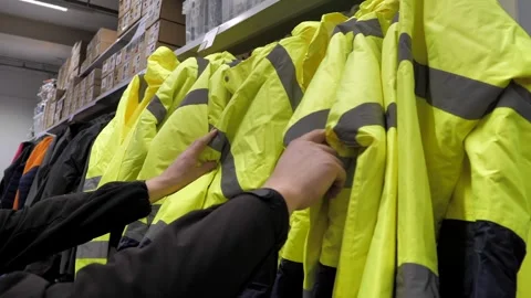 A man chooses work clothes with reflective elements.jackets for workers hang Stock Footage 297816198