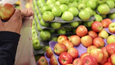 Man choosing apples in a grocery store. Close up of a mans hand with apples Stock Footage 235147046