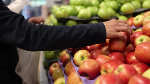 Man choosing apples in a grocery store. Close up of a mans hand with apples Stock Footage 235147626