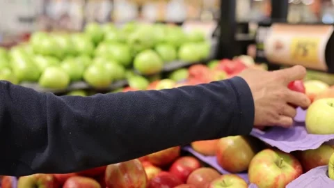 Man choosing apples in a grocery store. Close up of a mans hand with apples Stock Footage 235147728