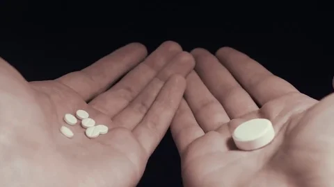 Man choosing between several small pills and one big pill on his hands POV Stock Footage 69212032