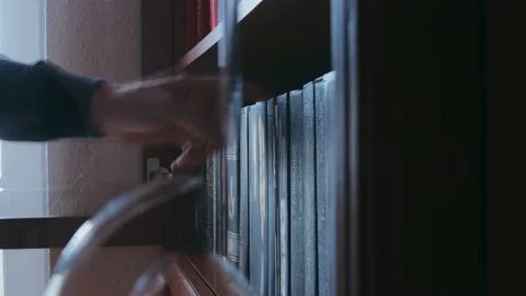 A man choosing a book from a bookshelf Видео 224894855