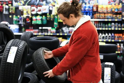 Man choosing a car tire in an auto parts store surrounded by wheels and veh.. Stock Photos