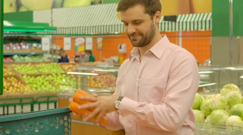 Man choosing carrots in grocery store Stock Footage 63374017