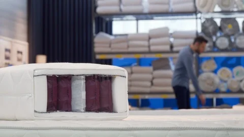 Man choosing comfortable orthopedic bed and mattress at furniture store Stock Footage 110264648