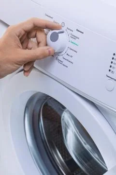 Man Choosing Cycle Program On Washing Machine Foto stock