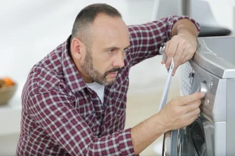 Man choosing cycle program on washing machine Stock Photos