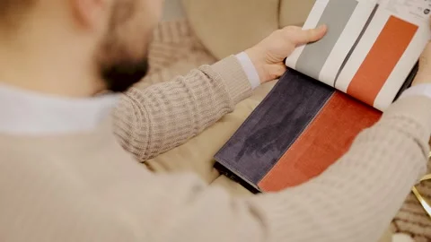 Man choosing fabric samples for home interior design, selecting textile swatches Stock Footage 334654207
