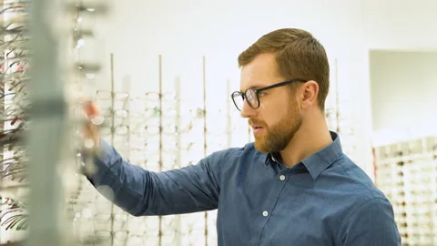 A man choosing glasses at optics store. Health care, eyesight and vision concept Stock Footage 231681855