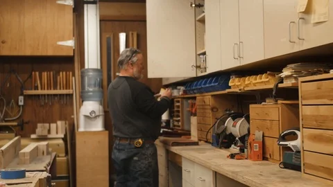 Man choosing glue from cabinet in workshop Stock Footage 102045022