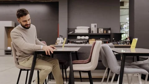 Man choosing new elegant dining table and chairs in modern furniture store Stock Footage 334654100