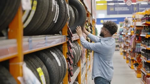 Man choosing new tires for his car in a store Video stock 336965448