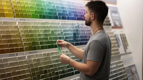 Man choosing paint chips or swatches in a hardware store. Concept of home Stock Footage 280187047