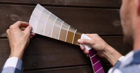 Man choosing paint color from samples palette for wooden plank house exterior Stock Footage 341877940