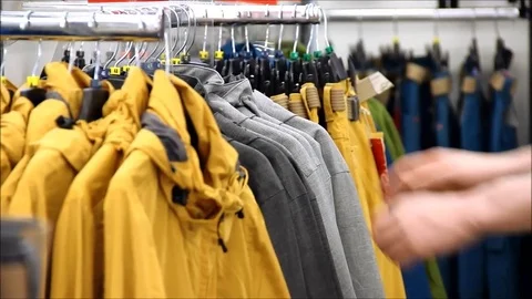 A man choosing the right size jacket from a rack Stock Footage 77861027