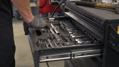 A man choosing the right tools in a gray metal tool cabinet at a service station Stock Footage 335681055