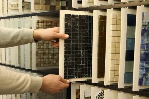 Man choosing tile among different samples in store, closeup Stock Photos