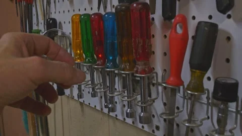 A man choosing a tool from a pegboard in his workshop Stock Footage 337376225