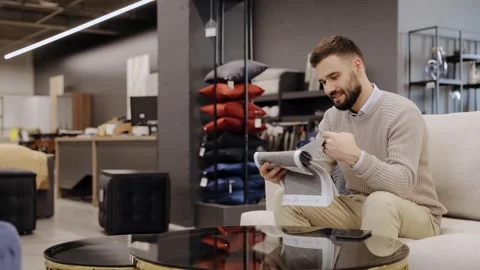 Man choosing upholstery fabric samples in furniture store Stock Footage 322550176
