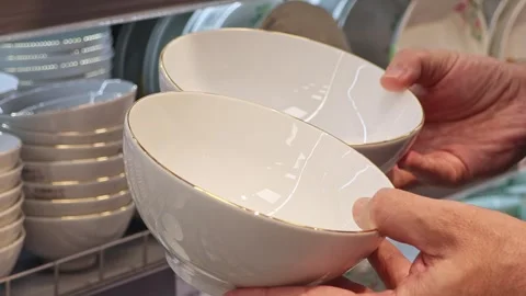 Man choosing white ceramic bowls in supermarket kitchenware department 動画素材 337736210