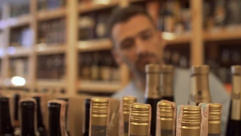The man choosing wine for a festive dinner. Guy who choosing the wine in the Stock Footage 99384821