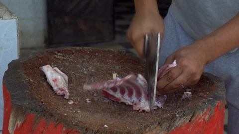 A man is chopping with a cleaver fresh meat of a ram. Man cuts bones for frying 스톡 동영상 120599550