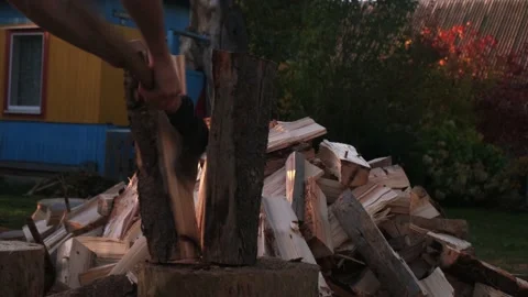 A man is chopping firewood with an axe, preparing for winter in the village Stock Footage 221712851