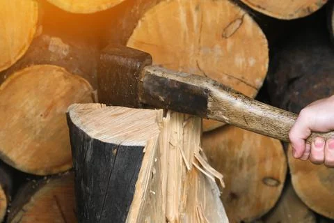 A man is chopping logs with an axe on chopping block. Harvesting of firewood Stock Photos