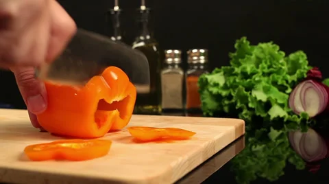 Man chopping orange bell pepper on a cutting board Stock Footage 39948498
