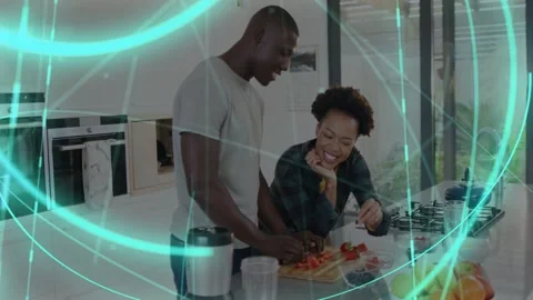 Man chopping tomatoes starting meal prep, woman accepting bite, teal holo band Stock Footage 333192910