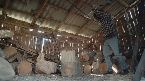 Man chopping wood inside the barn with beautiful sun rays light Vidéo 82715107
