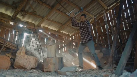 Man chopping wood inside the barn with beautiful sun rays light Video stock 82715239