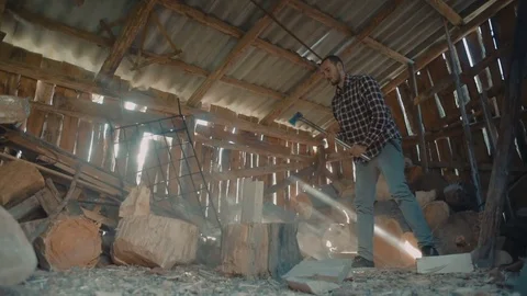 Man chopping wood inside the barn with beautiful sun rays light 스톡 동영상 82715529
