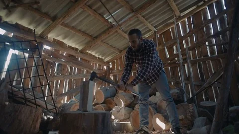 Man chopping wood inside the barn with beautiful sun rays light Видео 82715775