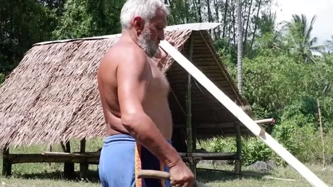 A man chops bamboo with a machete. They build a house. Video stock 158848683