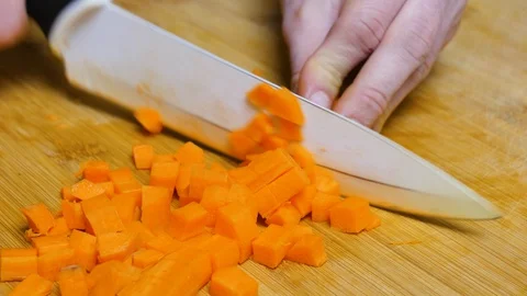 The man chops the carrot. Close shot of a carrot. 4K 스톡 동영상 128593547