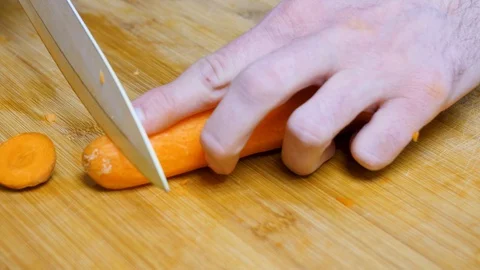 The man chops the carrot. Close shot of a carrot. 4K Stock Footage 128593749